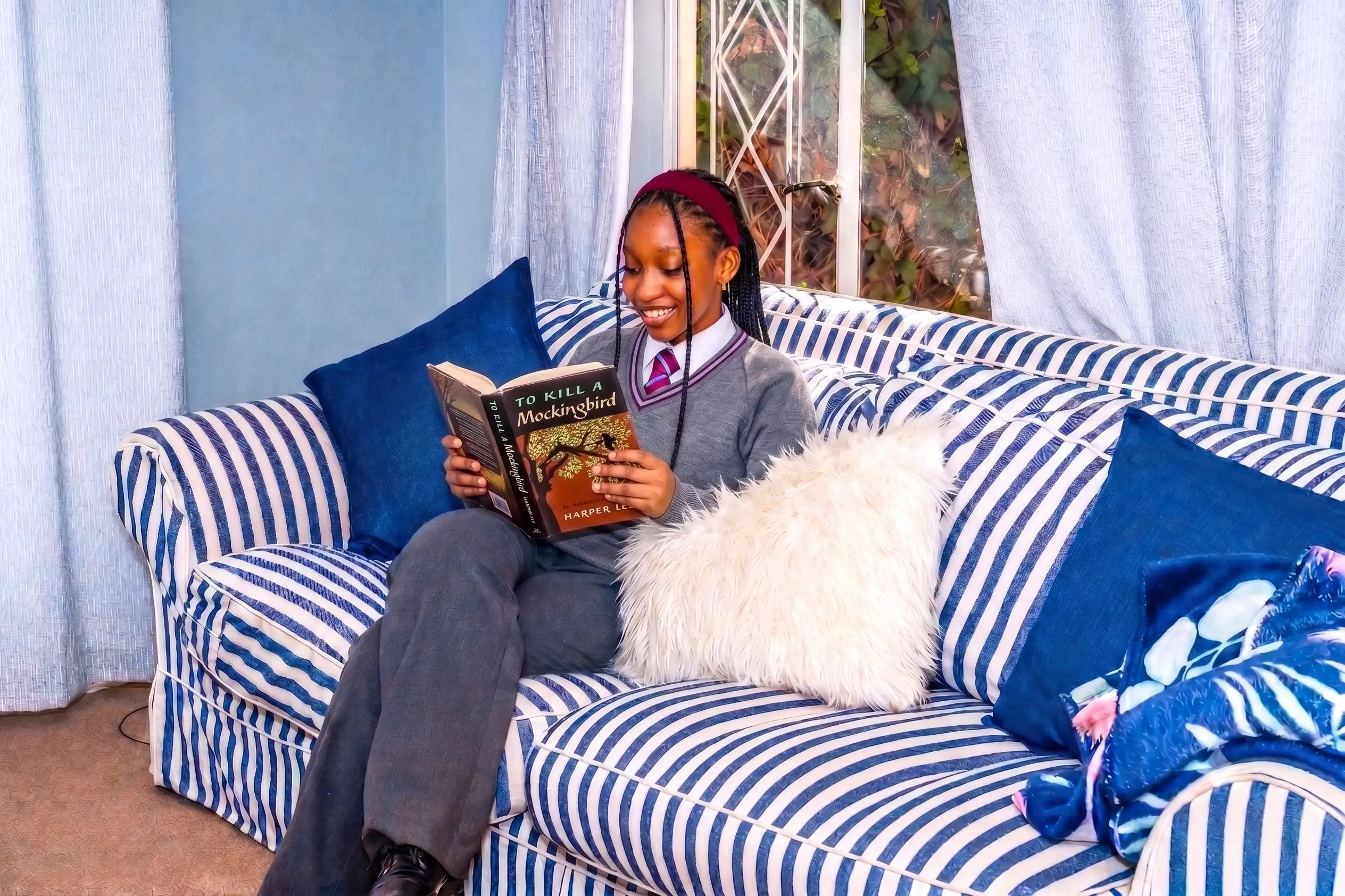 high school girl reading a book on a comfortable couch