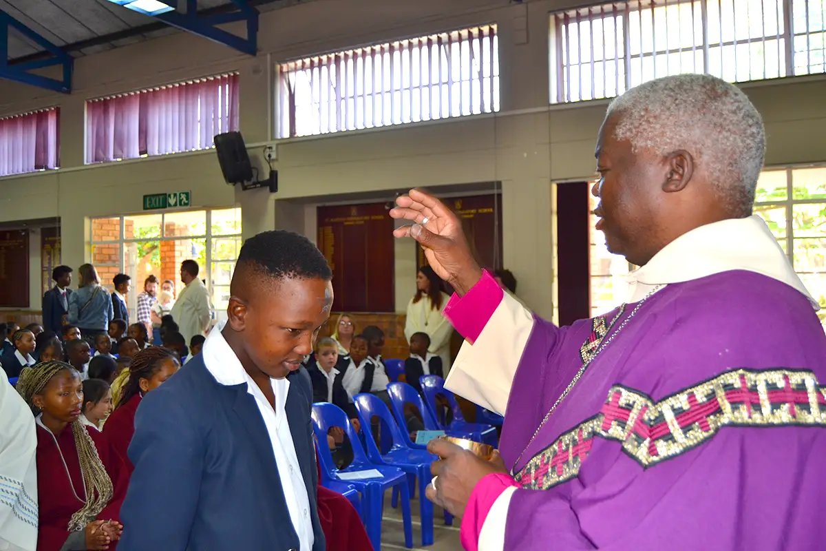 Pastor blessing a student during service