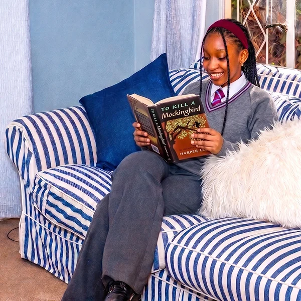 High school girl reading a book on a comfortable couch feat image